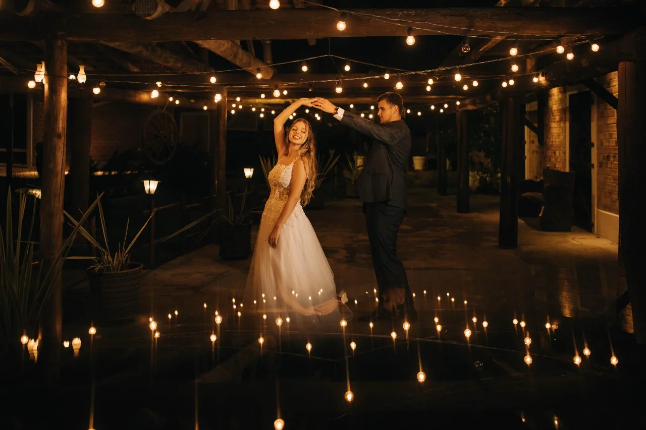 Casal celebrando sob um teto de luzes.