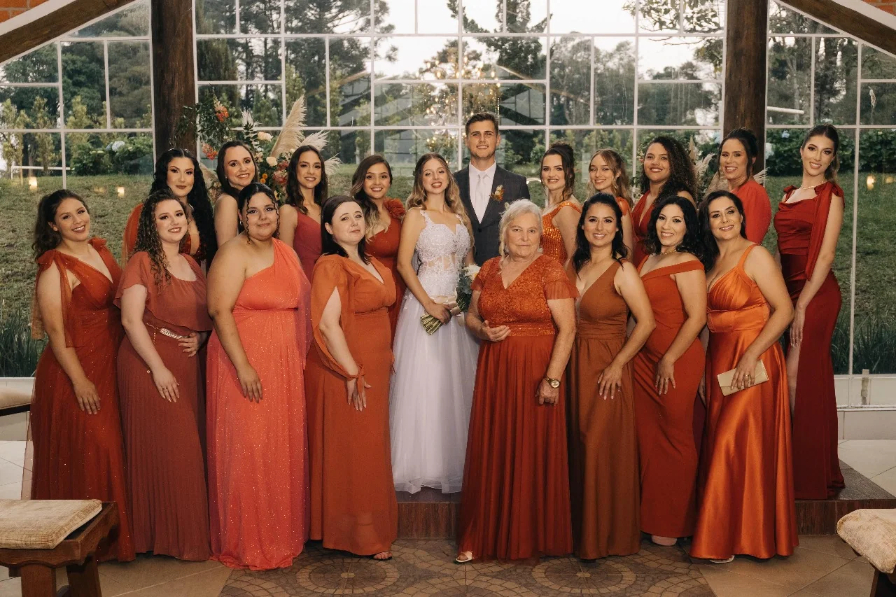 Noivos com familiares e madrinhas durante o casamento.