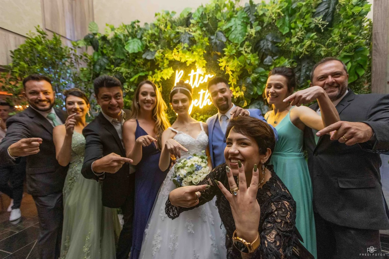 Juliana Porto sorrindo com noivos, familiares e clientes durante uma celebração